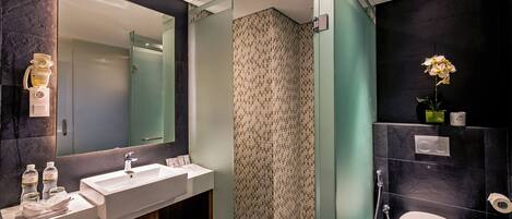 A modern bathroom with a large mirror, a sink, and a toilet.