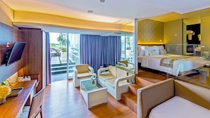 Une chambre d’hôtel moderne dotée d’un grand lit, d’un coin salon avec des fauteuils et une table, d’une télévision et d’un balcon offrant une vue agréable.