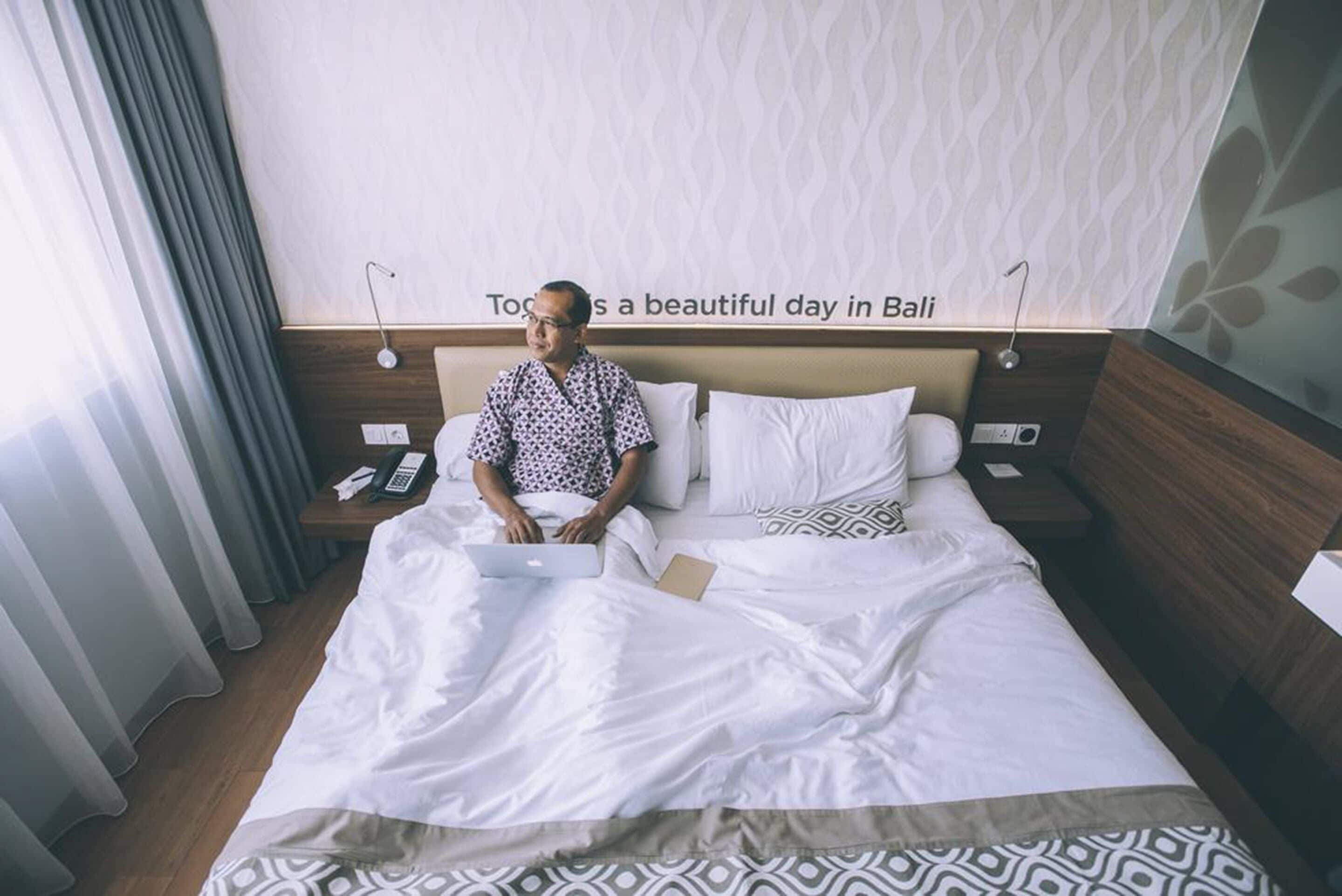 Habitación de hotel con cama, mesita de noche con teléfono y pared mostrando un mensaje de texto.