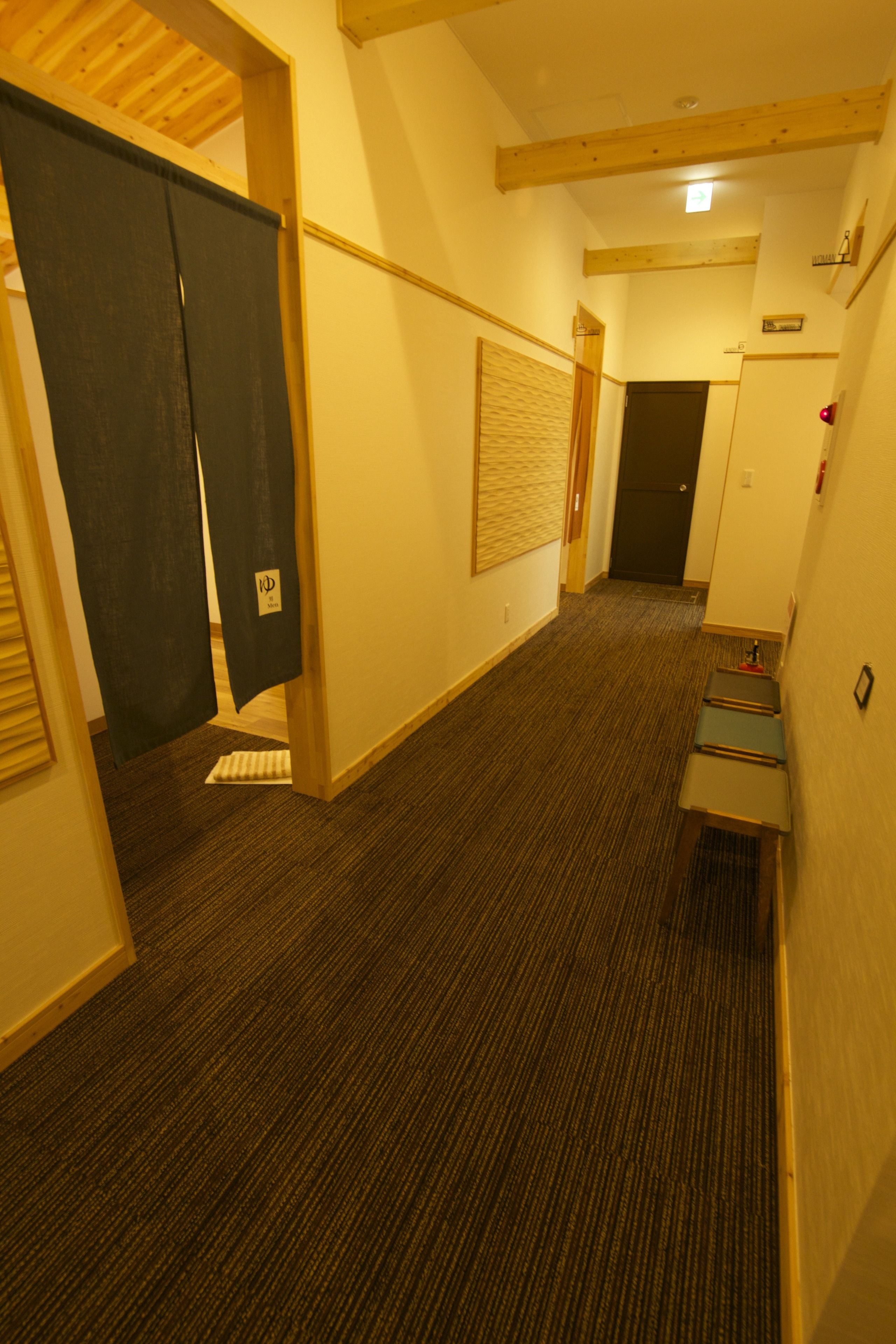 Un pasillo de hotel con pisos alfombrados, vigas de madera en el techo y una puerta con un letrero.