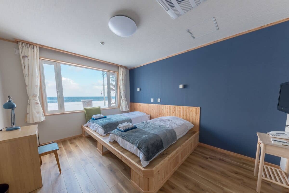 A bedroom with two beds, a desk, and a TV.