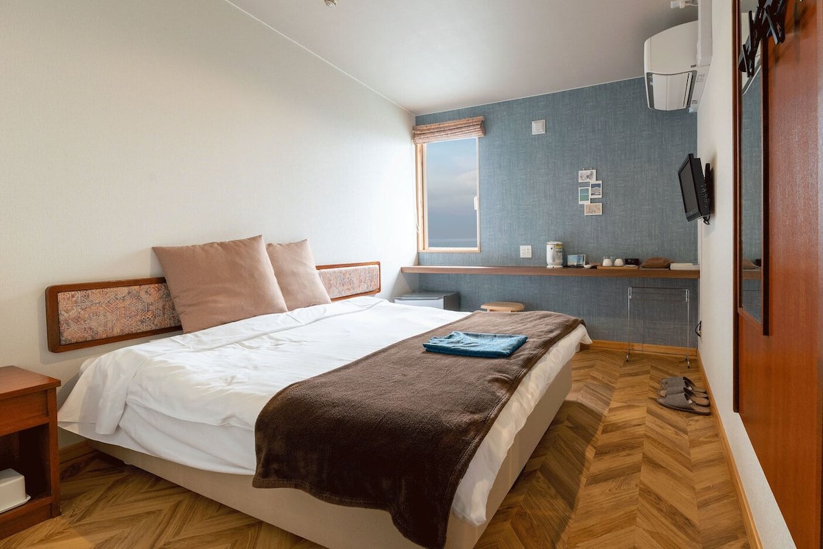 A bedroom with a bed, bedside table, and a small desk area with a chair.
