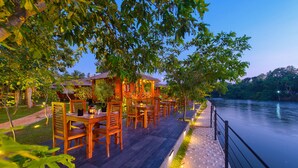 Une terrasse extérieure en bois, dotée de tables et de chaises, qui offre une vue sur un lac paisible.