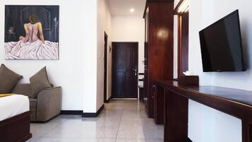 Habitación de hotel con cama, sofá, televisión, un cuadro y un armario de madera.
