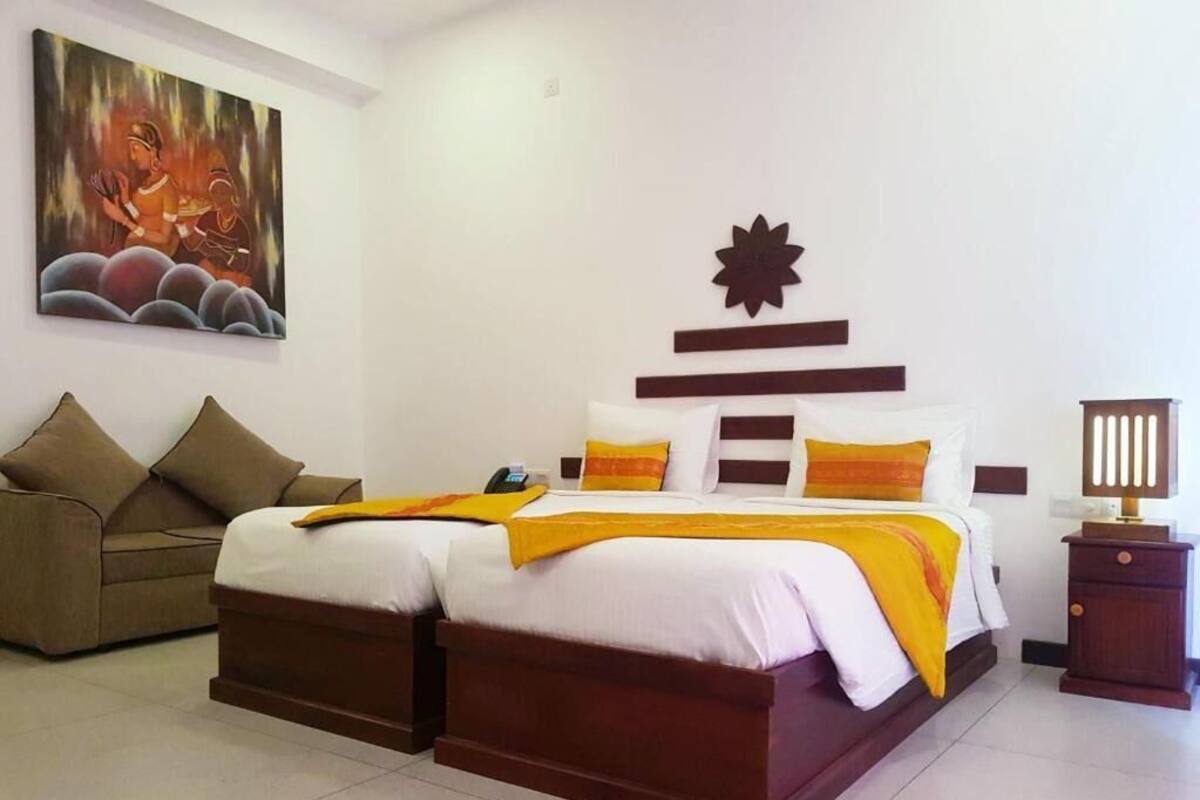 Un lit double avec une literie blanche et jaune, une tête de lit marron et un élément décoratif mural.