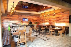 A restaurant with wooden walls, multiple seating areas, and hanging pendant lights.