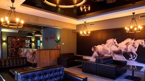 Un hall d’hôtel doté de sièges en cuir, d’un comptoir d’accueil et d’une grande fresque représentant un cheval.