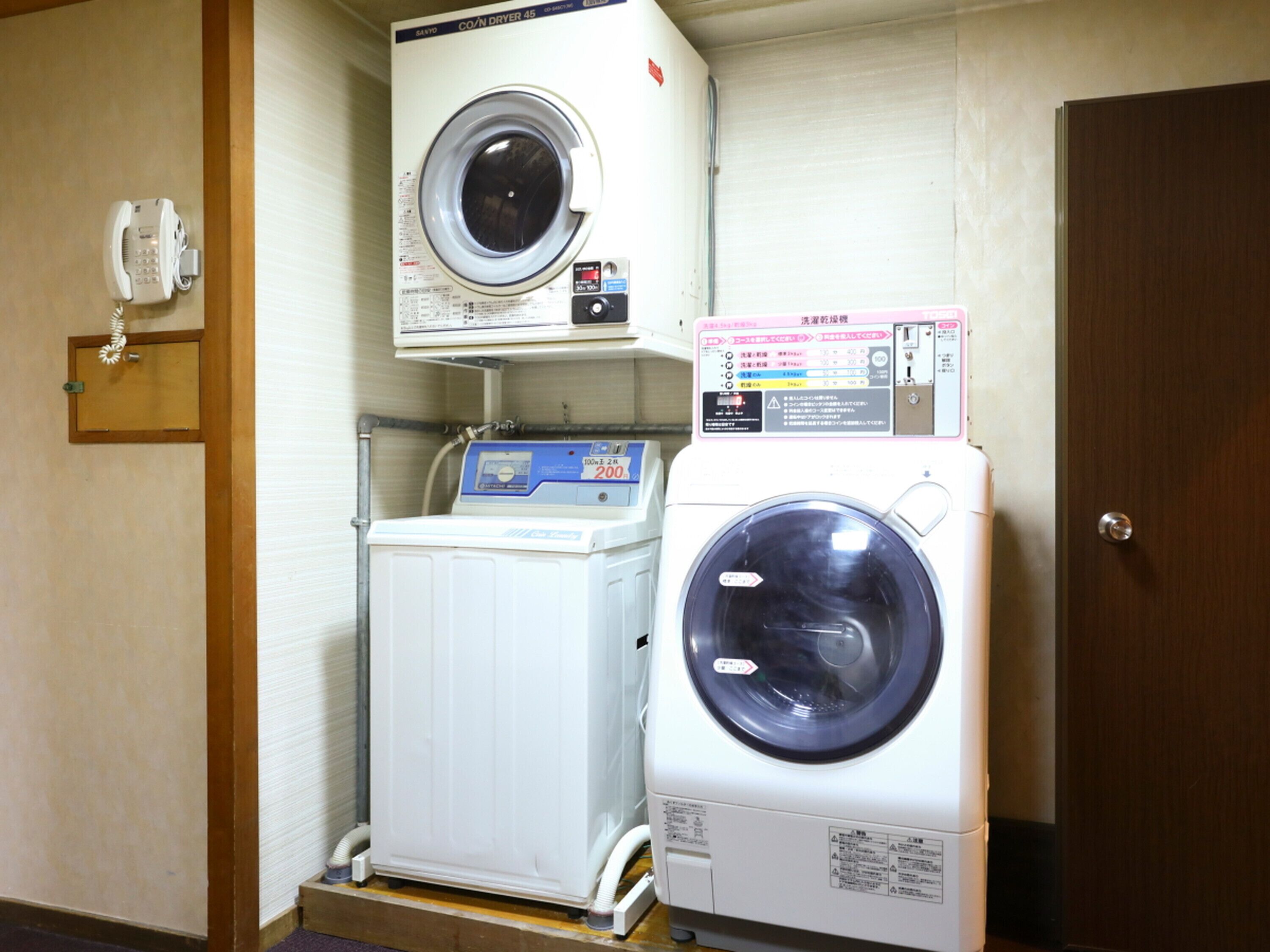 A laundry room with two washing machines, a dryer, and a telephone.