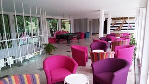 A modern lounge area with vibrant pink and multicolored chairs, a pool table, and a striped partition. - Tintyava Park Hotel (Varna)