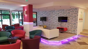 A modern lounge area with colorful chairs, a white sofa, and a wall with city names. - Tintyava Park Hotel (Varna)