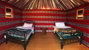 A room with two beds, patterned walls, and a wooden floor. - Mohammed Mutlak Camp (Wadi Rum)