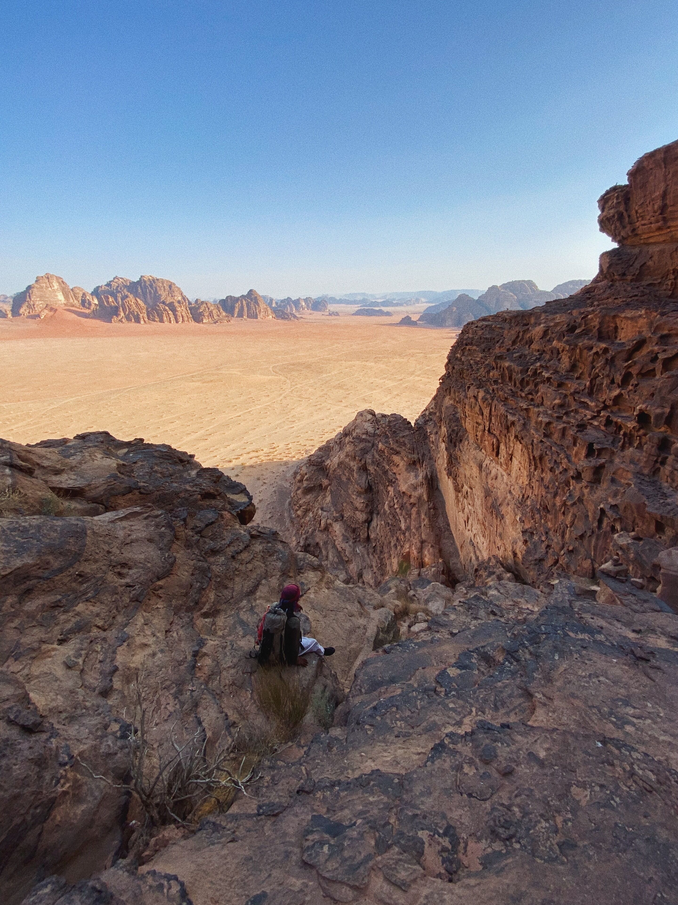 A rocky terrain with a person sitting on a rock.