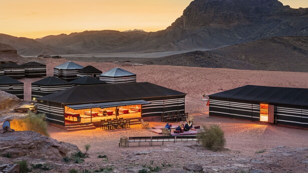 A desert camp with yurts, a central communal area with seating and a fire pit, and a view of the surrounding mountains. - Mohammed Mutlak Camp (Wadi Rum)