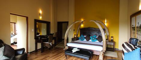 A spacious bedroom with a large bed, a wooden bench, a leather armchair, and a sofa.
