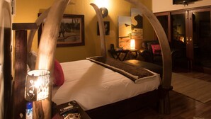 A room with a bed, a lamp, a TV, and a wooden ceiling. - Phumelelo Lodge (Bela-Bela)