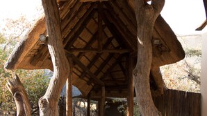 A wooden structure with a thatched roof and a wooden walkway. - Phumelelo Lodge (Bela-Bela)