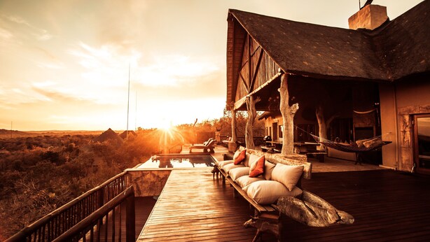 A wooden deck with outdoor seating, a pool, and a view of the landscape. - Phumelelo Lodge (Bela-Bela)