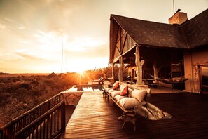 Una terraza de madera con mobiliario exterior, una piscina y vistas del paisaje.