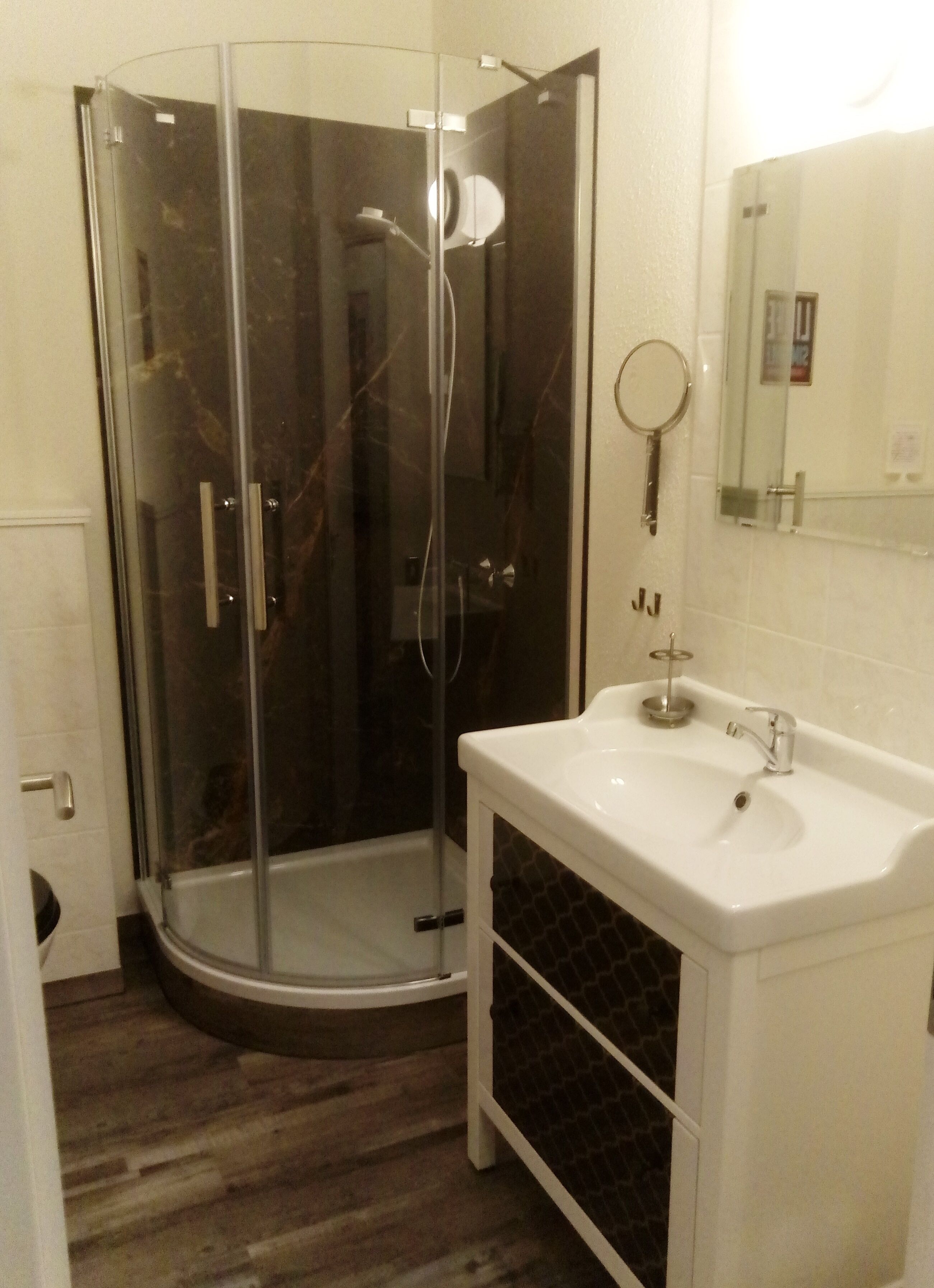 Une salle de bain avec une douche à parois de verre, un lavabo blanc et un miroir.