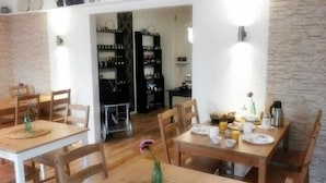 A dining area with wooden tables and chairs, a buffet setup, and a kitchen visible in the background. - Villa Regina (Moehnesee)