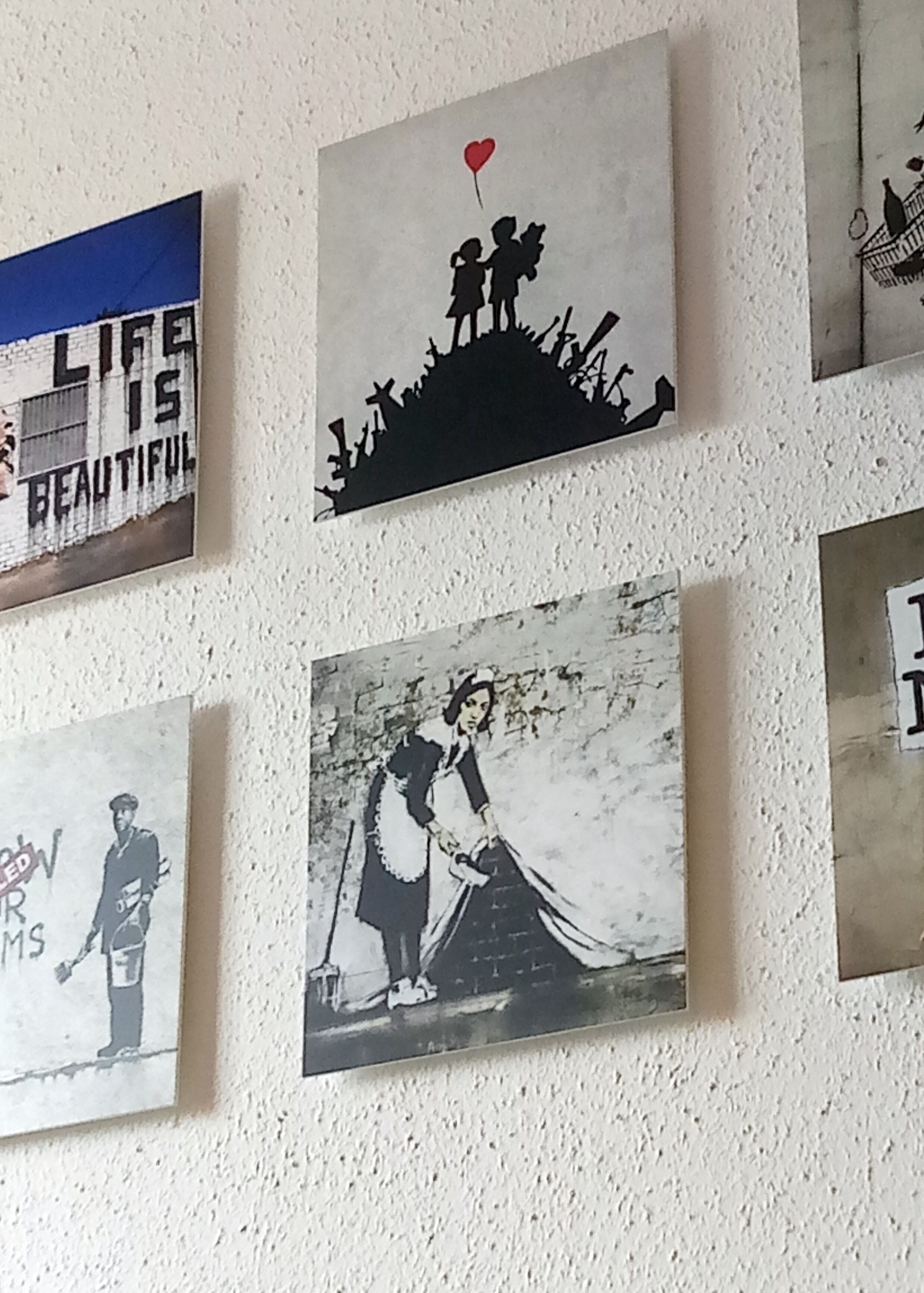Eine Wand mit sechs gerahmten Kunstwerken.