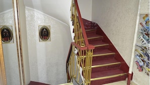 A staircase with red steps and gold railings, leading to a landing with a white wall and a decorative emblem. - Hotel Ekol (Istanbul)