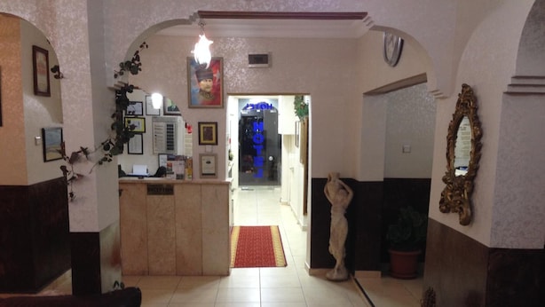 A hotel reception area with a reception desk, a clock, and a mirror on the wall. - Hotel Ekol (Istanbul)
