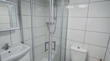 A modern bathroom with a glass-enclosed shower, a white sink, and a toilet.