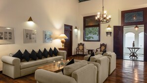 A spacious living area with a high ceiling, wooden flooring, and a seating arrangement including a sofa and armchairs. - Green Casa (Galle)
