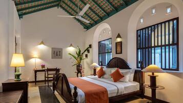 Habitación de hotel con cama, mesitas de noche, lámparas, una planta en maceta y vistas al exterior.