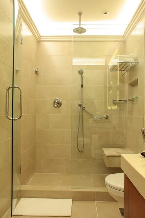 Un baño moderno con ducha envuelta en vidrio, inodoro y lavamanos con espejo.