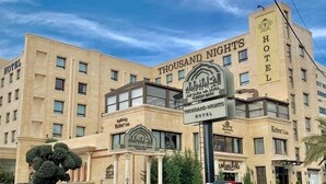 A large hotel with multiple floors and a prominent sign for 'Thousand Nights Hotel'. - Thousand Nights Hotel Amman (Amman)