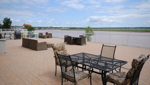 Un patio al aire libre con una mesa, sillas, una parrilla y vistas a un río.