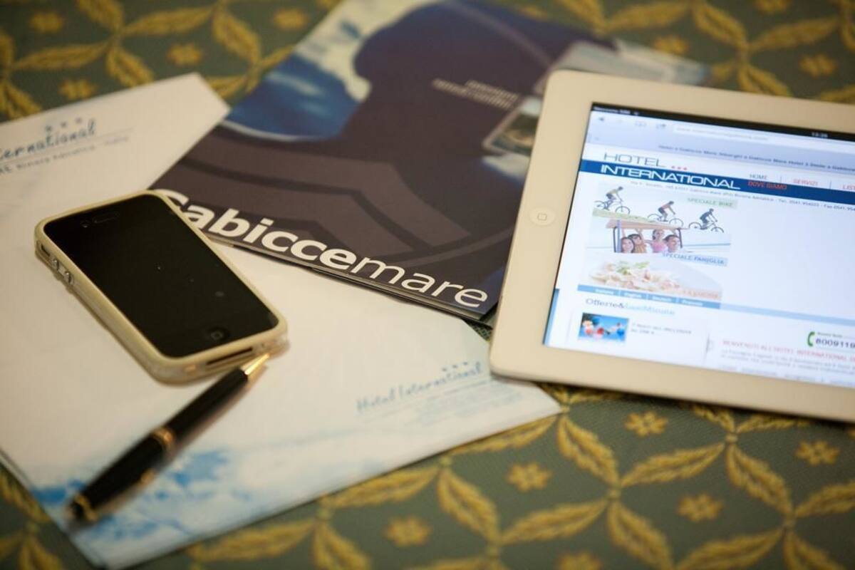 A tablet displaying a hotel website, a smartphone, and a brochure with the name "Cabiccemare".