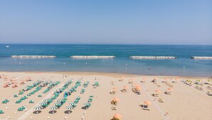 A beach with rows of sunbeds and umbrellas, a clear sky, and calm sea. - Hotel International (Gabicce Mare)