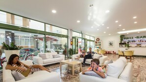 A spacious lobby with white sofas, a coffee table, and a bar area with a sign reading "HALL BAR". - Hotel International (Gabicce Mare)