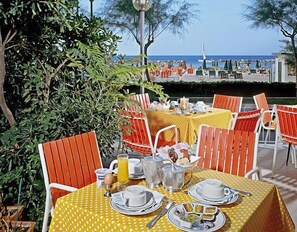 A table set for breakfast with a view of the sea, surrounded by orange chairs and yellow tablecloths. - Hotel International (Gabicce Mare)
