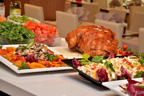 Een buffet met diverse gerechten, waaronder een gebraden kip, salades en groenten.