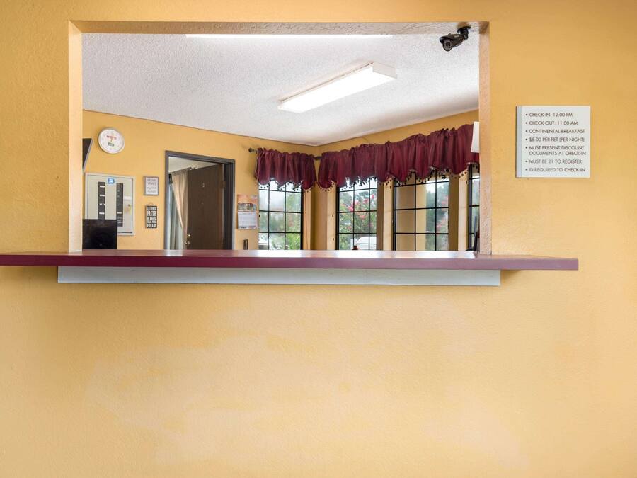 A reception area with a check-in counter, a clock, and a window with curtains.