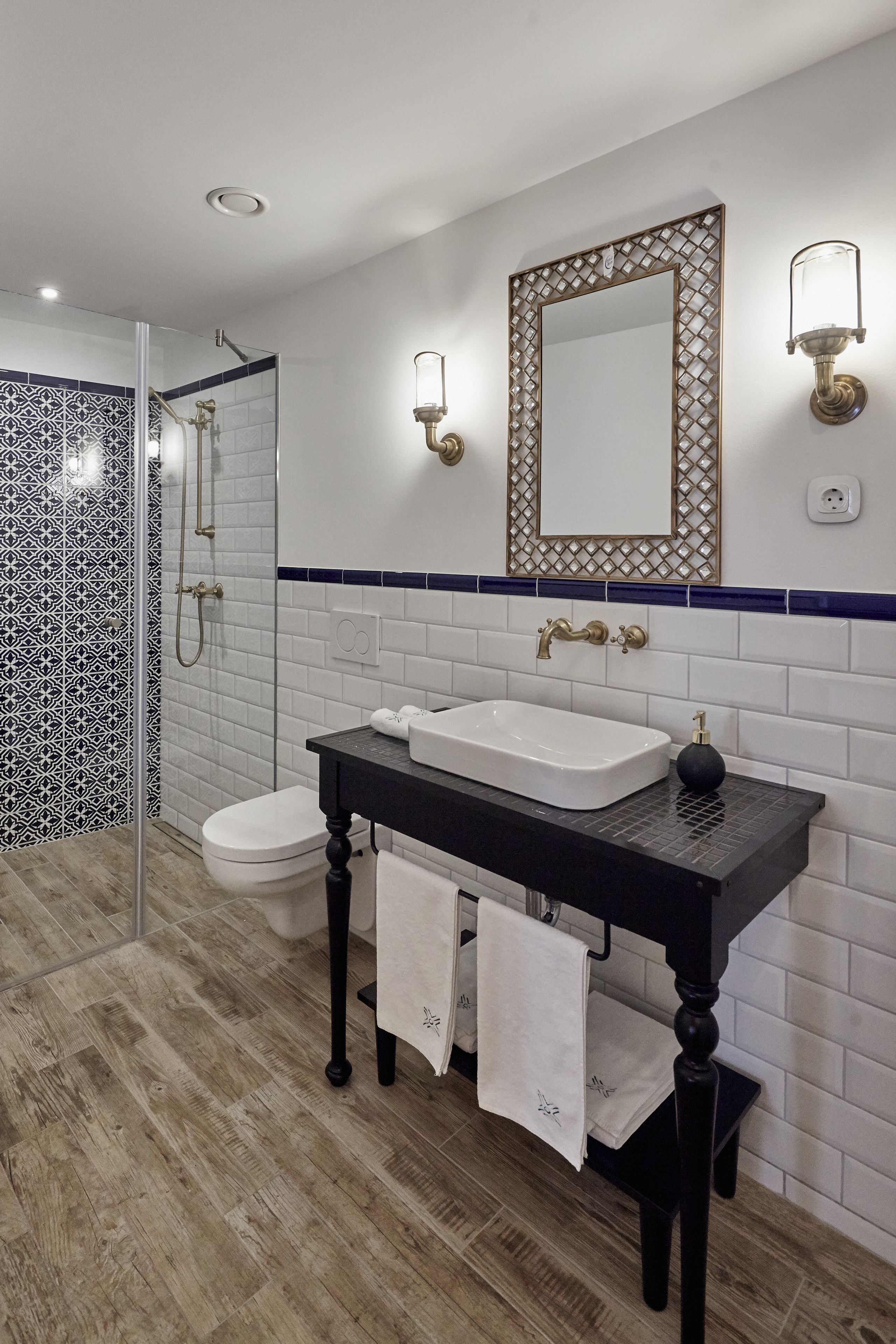 A modern bathroom with a white sink, black countertop, and a glass-enclosed shower.