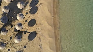 An aerial view of a beach with several large, round, dark objects scattered along the shoreline. - Parian Boutique Hotel (Paros)