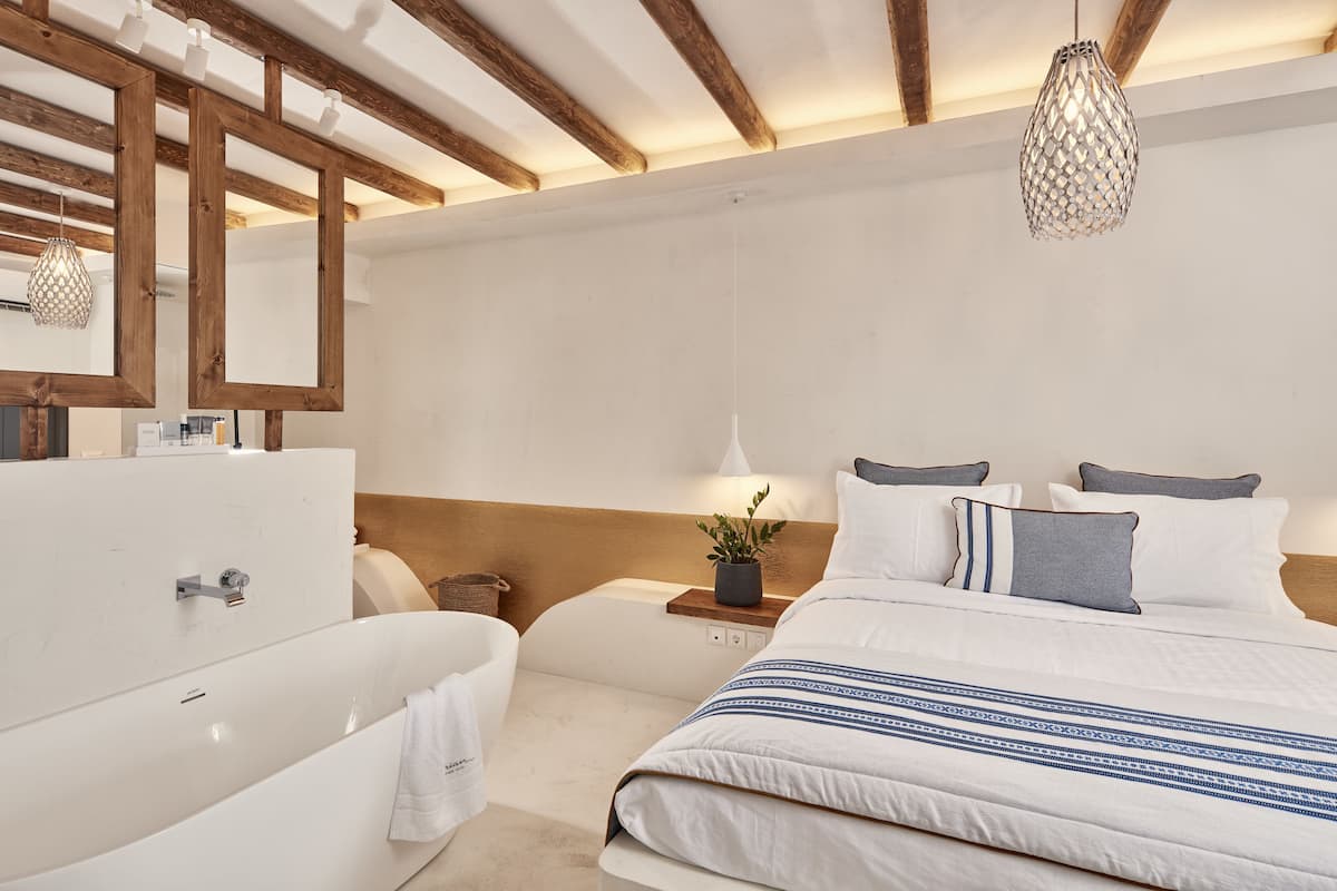 Un dormitorio moderno con una cama grande, una bañera blanca y un techo de madera.