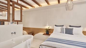 A modern bedroom with a large bed, a white bathtub, and a wooden ceiling.