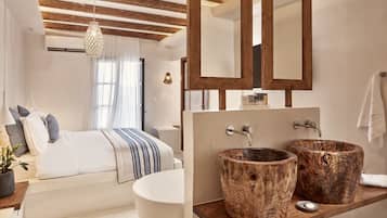 A modern bedroom with a large bed, a wooden ceiling, and a large mirror above the bathroom sink.
