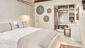 A bedroom with a bed, bedside tables, a wardrobe, and a mirror. - Parian Boutique Hotel (Paros)