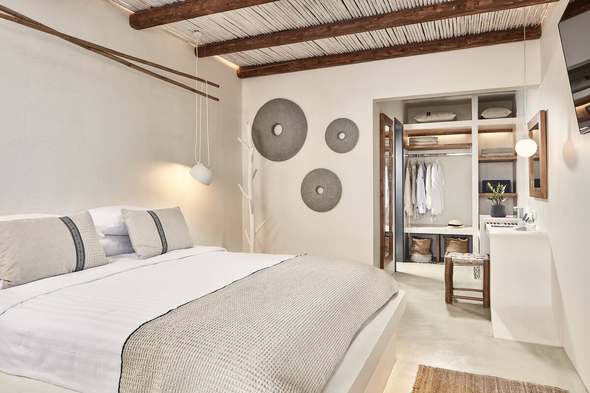 Un dormitorio con cama, mesitas de noche, un armario y un espejo.