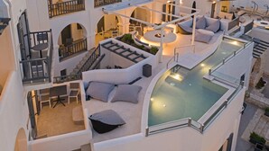 A rooftop pool area with a curved glass edge, outdoor seating with patterned cushions, and a fire pit. - Parian Boutique Hotel (Paros)