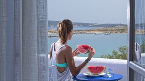 A person sitting at a table with a view of the sea and a slice of watermelon on the table. - Parian Boutique Hotel (Paros)