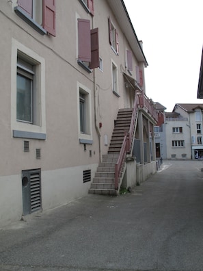 A building with a staircase leading to the entrance, a window with shutters, and a door. - Hôtel du Midi (Domene)