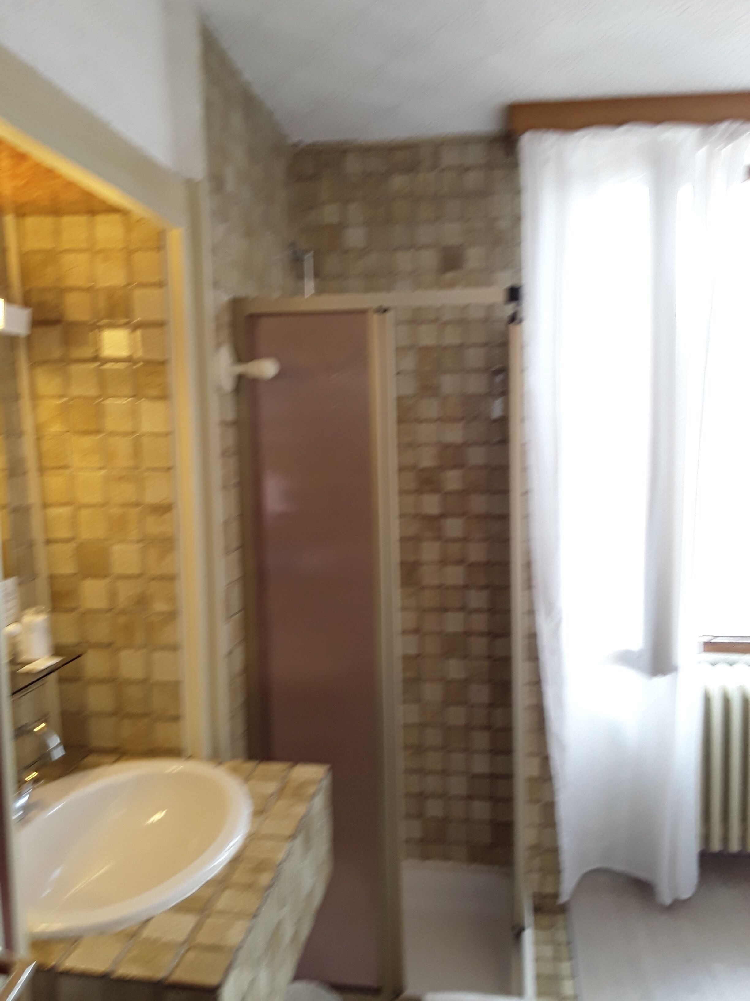 Une salle de bain avec un mur carrelé, une douche, un lavabo et des toilettes.
